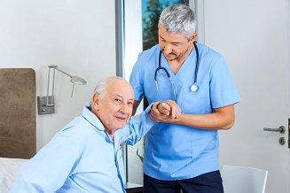 nurse assisting senior man to stand